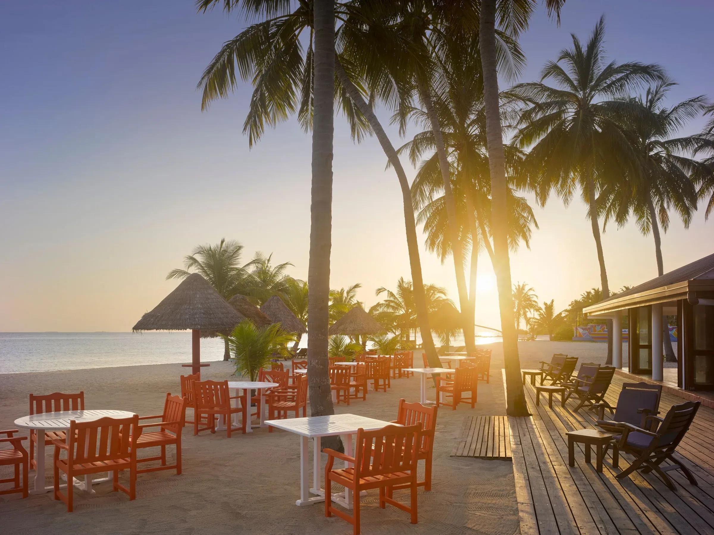 Tramonto mozzafiato sulla spiaggia incantevole del Villa Park Sun Island Resort & Spa, con eleganti tavoli pronti per una cena al chiaro di luna.